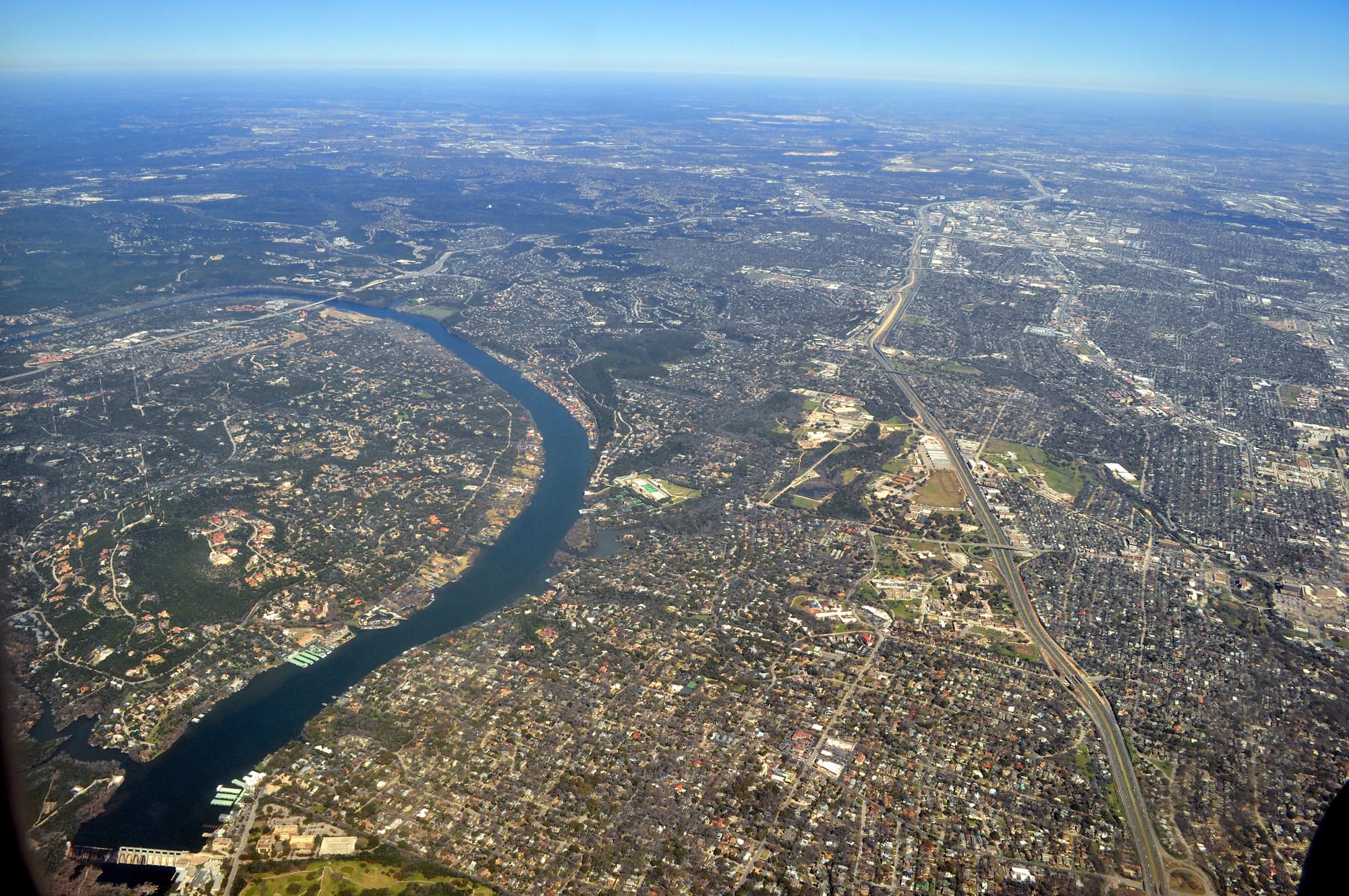 Aerial view of the Colorado River (Lake Austin) curving between the wooded hills of West Lake Hills and the Tarrytown neighborhood of Austin